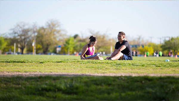 Photo of a man and woman sitting on Johnson Field on UNM Campus