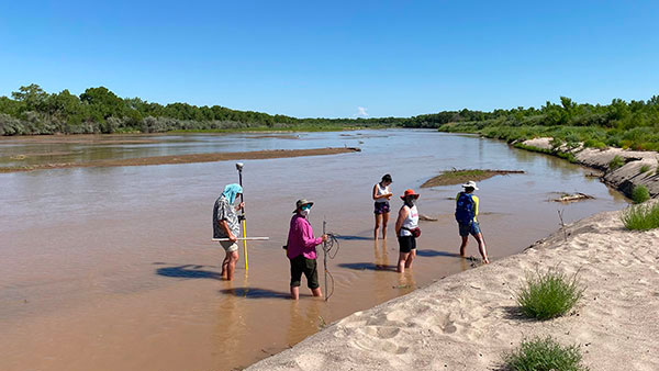 Photo of a group of people walking in the river