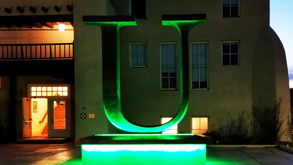 UNM's "U" statue lit up in green at night